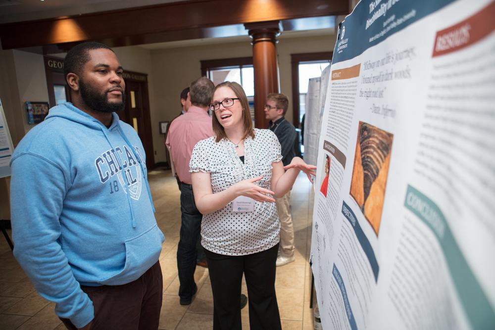 Student presenting their poster to a guest at the Graduate Showcase